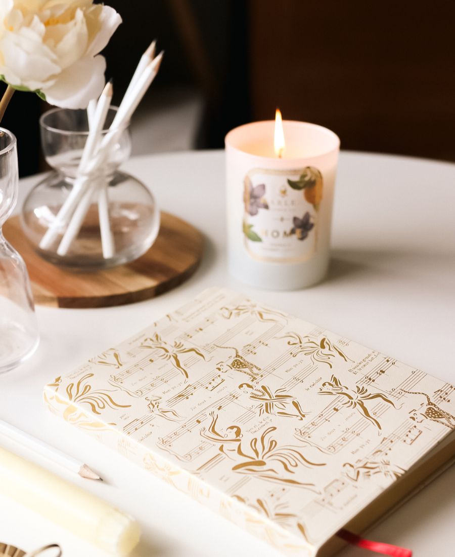 This is an image of our cream and gold, Josephine journal with our home, botanical candle illuminated in the background.