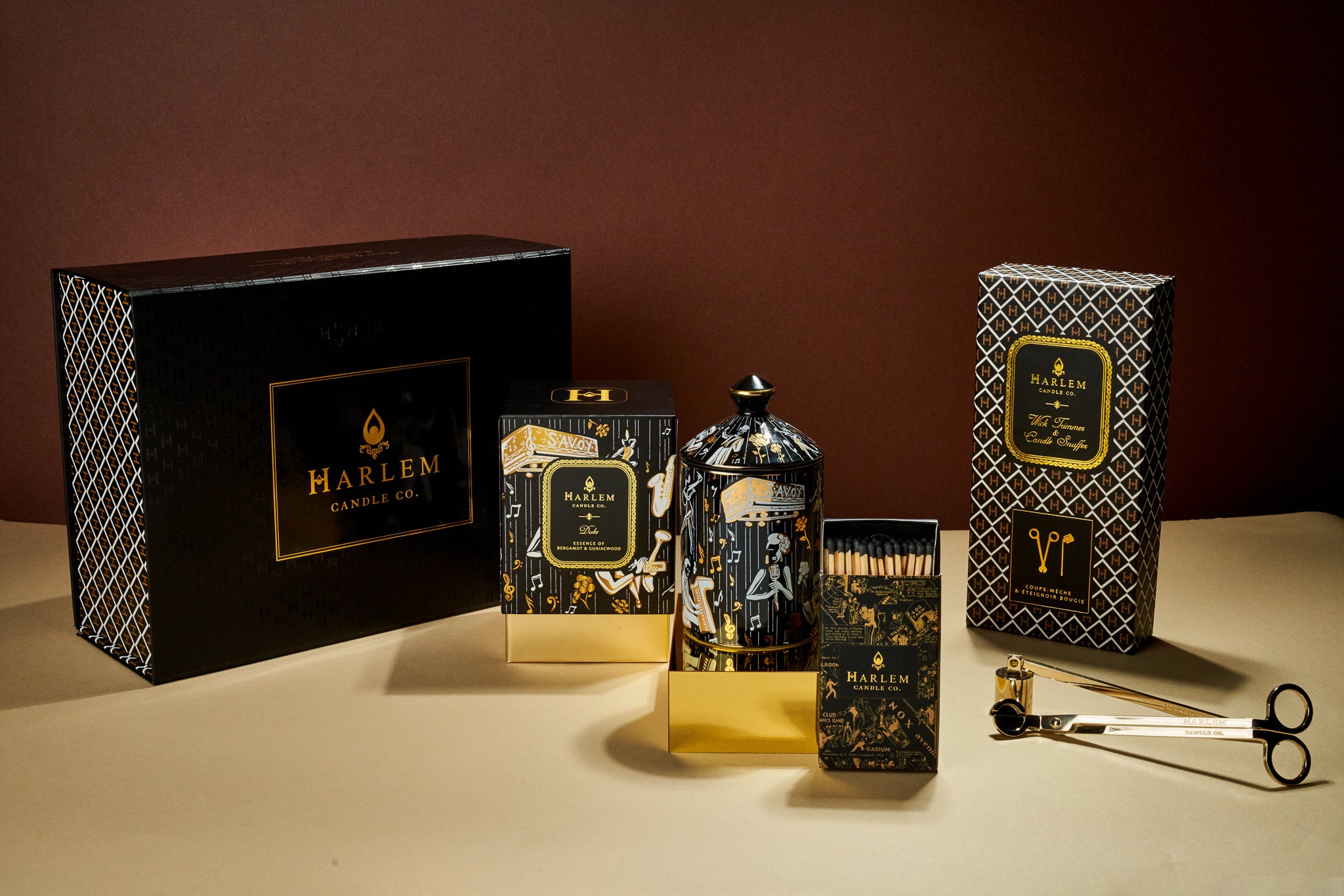 This is a lifestyle image of our Duke, ceramic gift box which include our 22 karat gold duke, ceramic candle, our gold and black nightclub map of Harlem matches, and our wick trimmer and snuffer set.